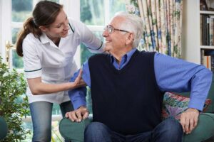 Senior residents enjoying time together in a bright, plant-filled common area with natural sunlight and energy-efficient lighting.