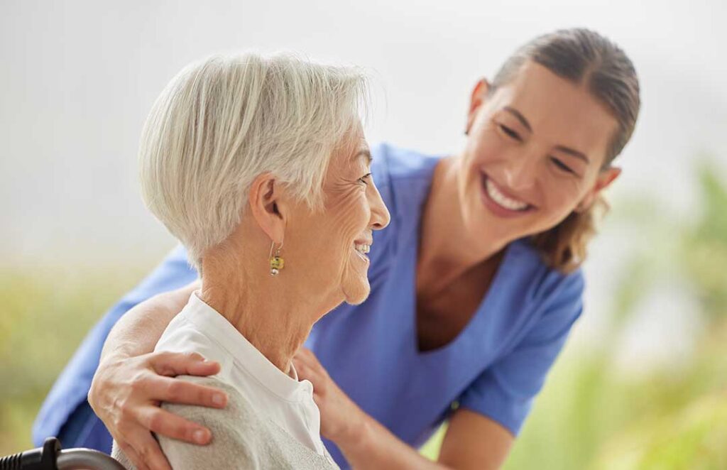 An older adult and family member sitting together, talking and reviewing a notepad in a comfortable home setting.