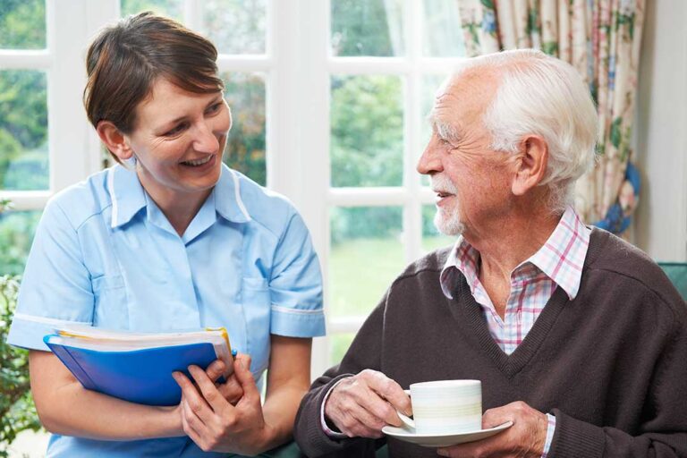 Older adult and family member reviewing medications and daily routines at a kitchen table.